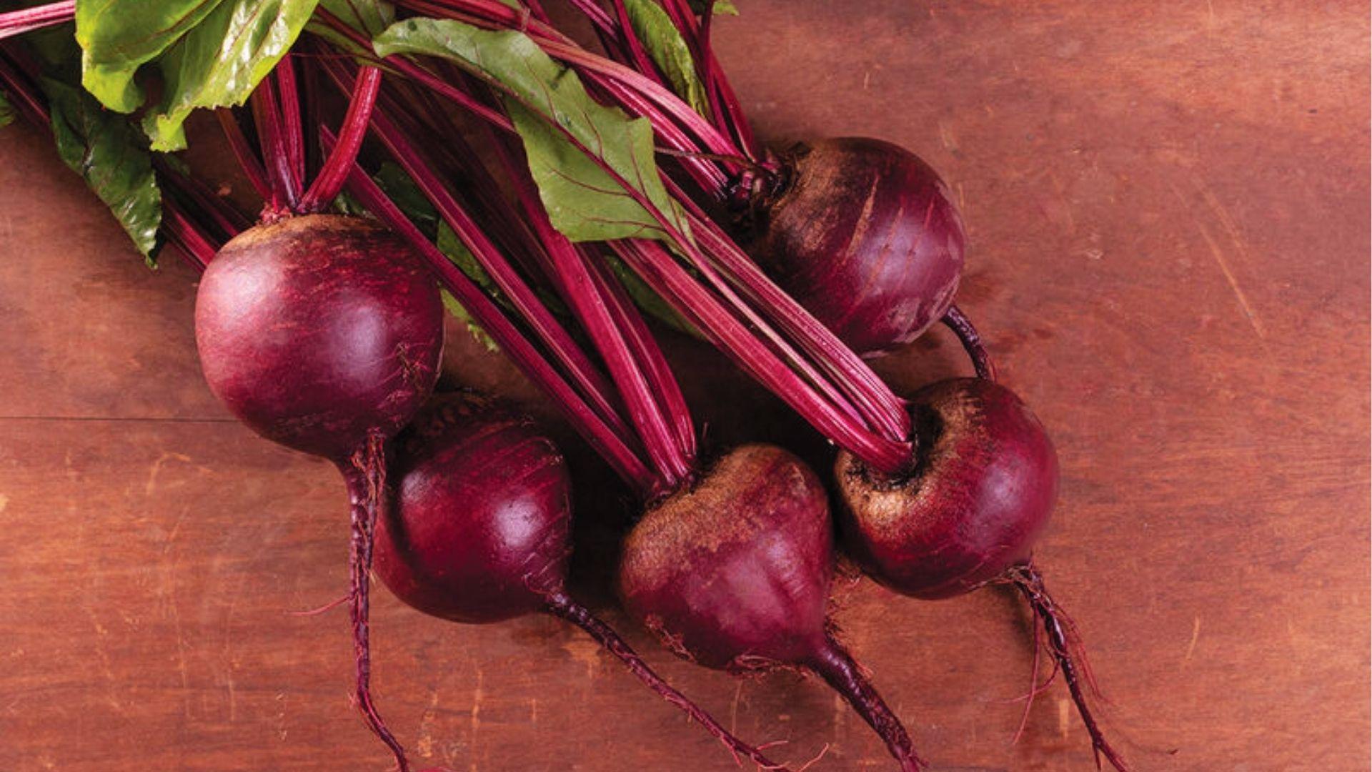 Bunch of Moneta with vivid magenta stems and green leaves resting on a wood background.